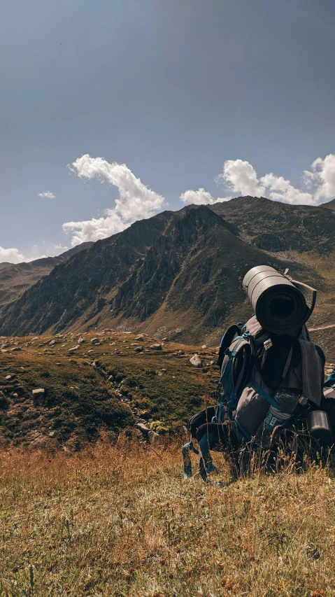 a backpack sitting on the grass in front of mountains