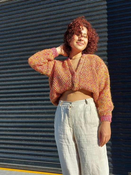 a woman poses for the camera wearing a colorful top and wide legged pants