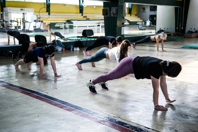 many people doing different stretching exercises in an athletic facility