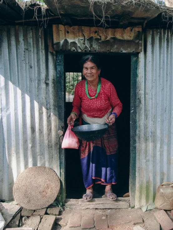 a woman is smiling while holding her food in front of a hut