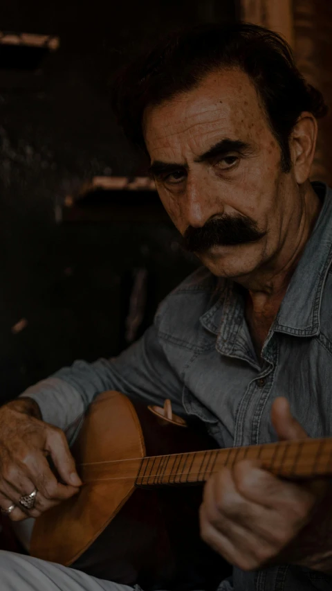 a man sitting down playing an acoustic guitar