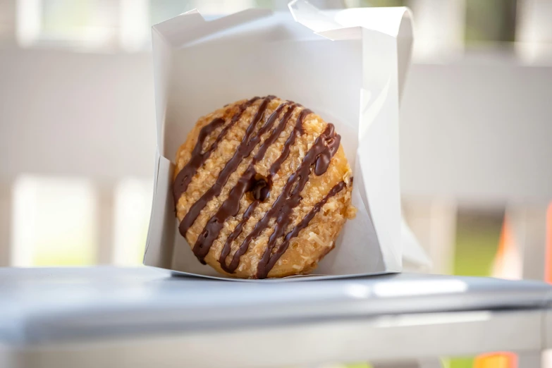 an unhealthy donut with chocolate sauce inside a paper bag