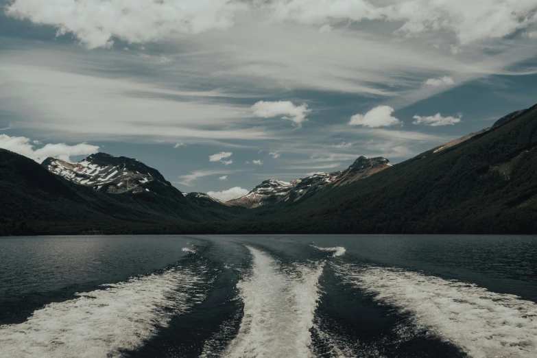 the wake of a speedboat in a lake surrounded by mountains