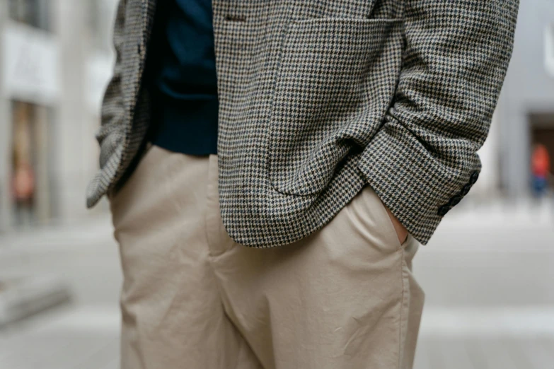 a man in a suit stands on a sidewalk with his hands on his hips