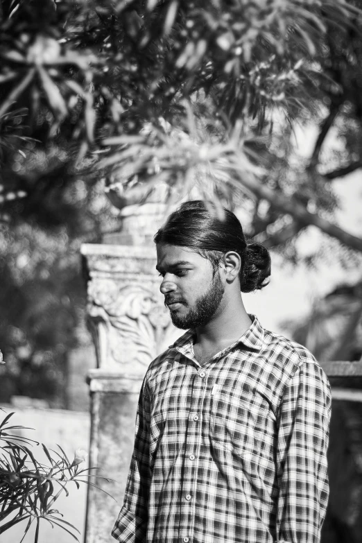 an indian man in plaid shirt looking at his phone