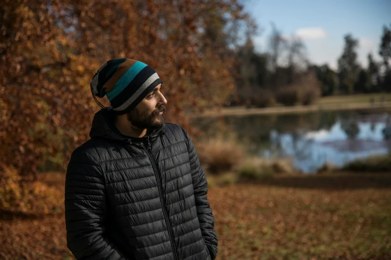 a man standing in front of trees with his head to his left