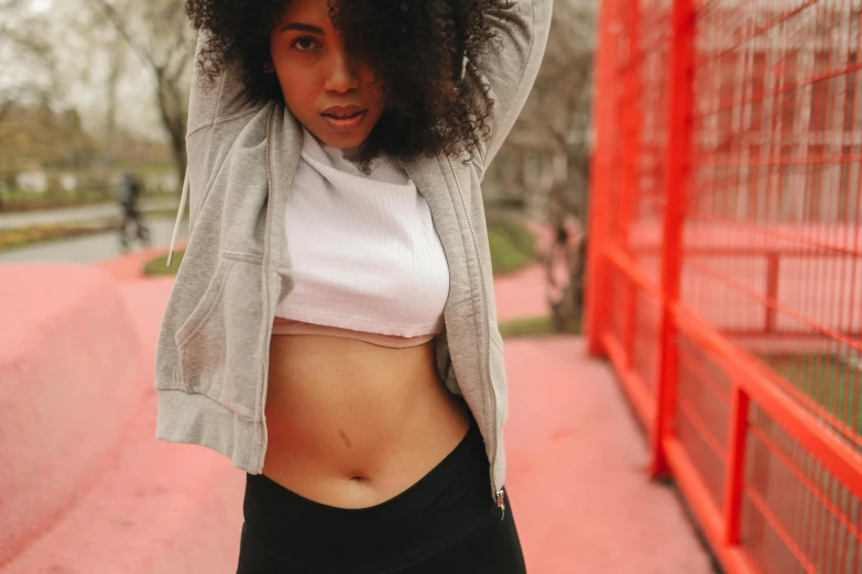 a young lady with a jacket and sports clothes on is holding her hair