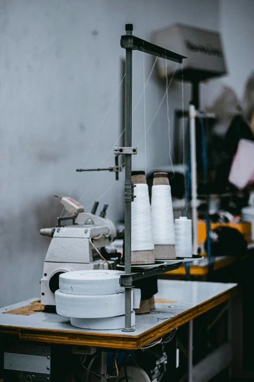 sewing machine with white thread on table next to other machines