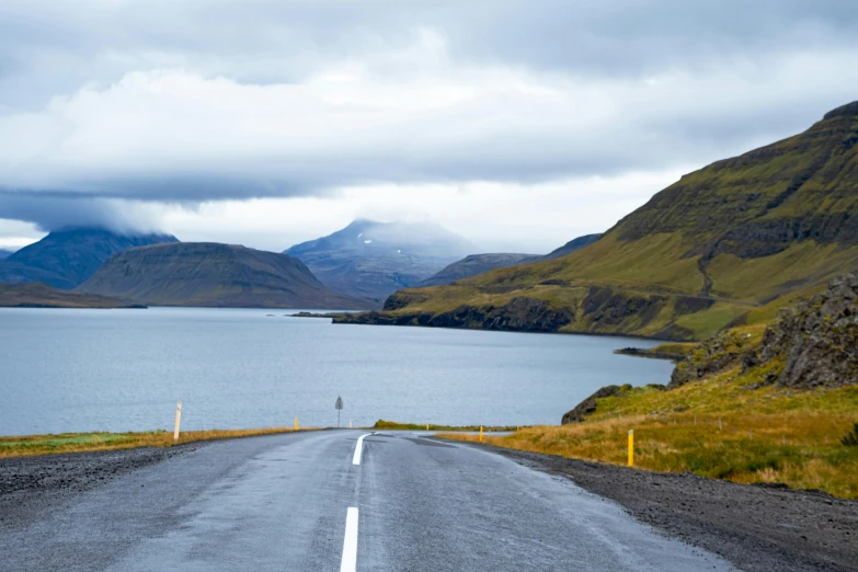 a road leading into the mountains by a lake