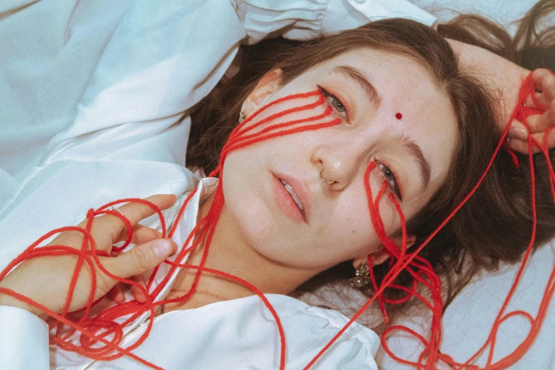 a woman laying in bed with several strings tied to her face