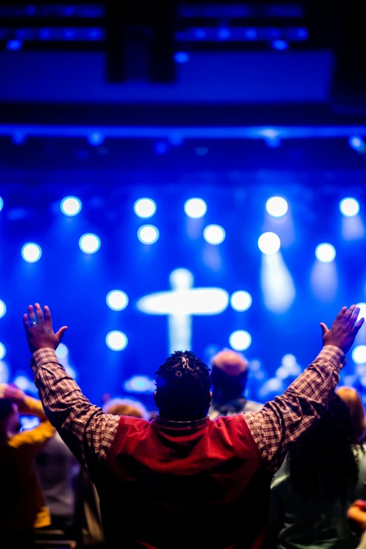 a man standing on stage with his hands in the air