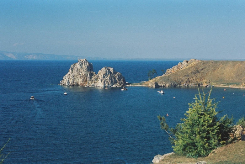 the shore has boats on it and rocky outcropping