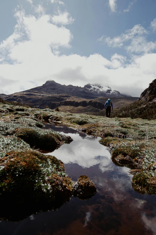 a man that is walking around a field with a reflection of the sky