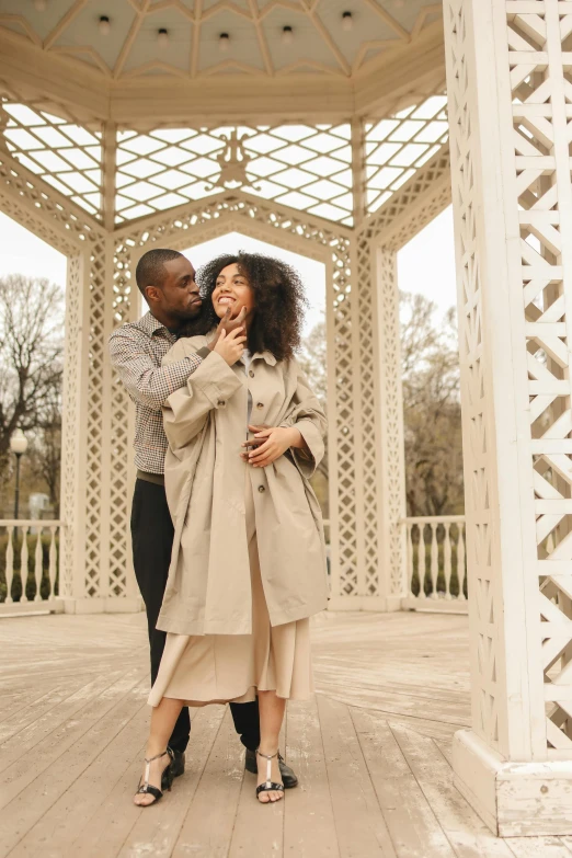 a couple smiling at each other while holding hands and cuddling in front of an archway