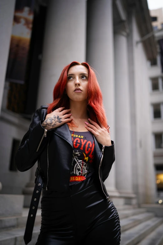 a woman with red hair standing on the sidewalk