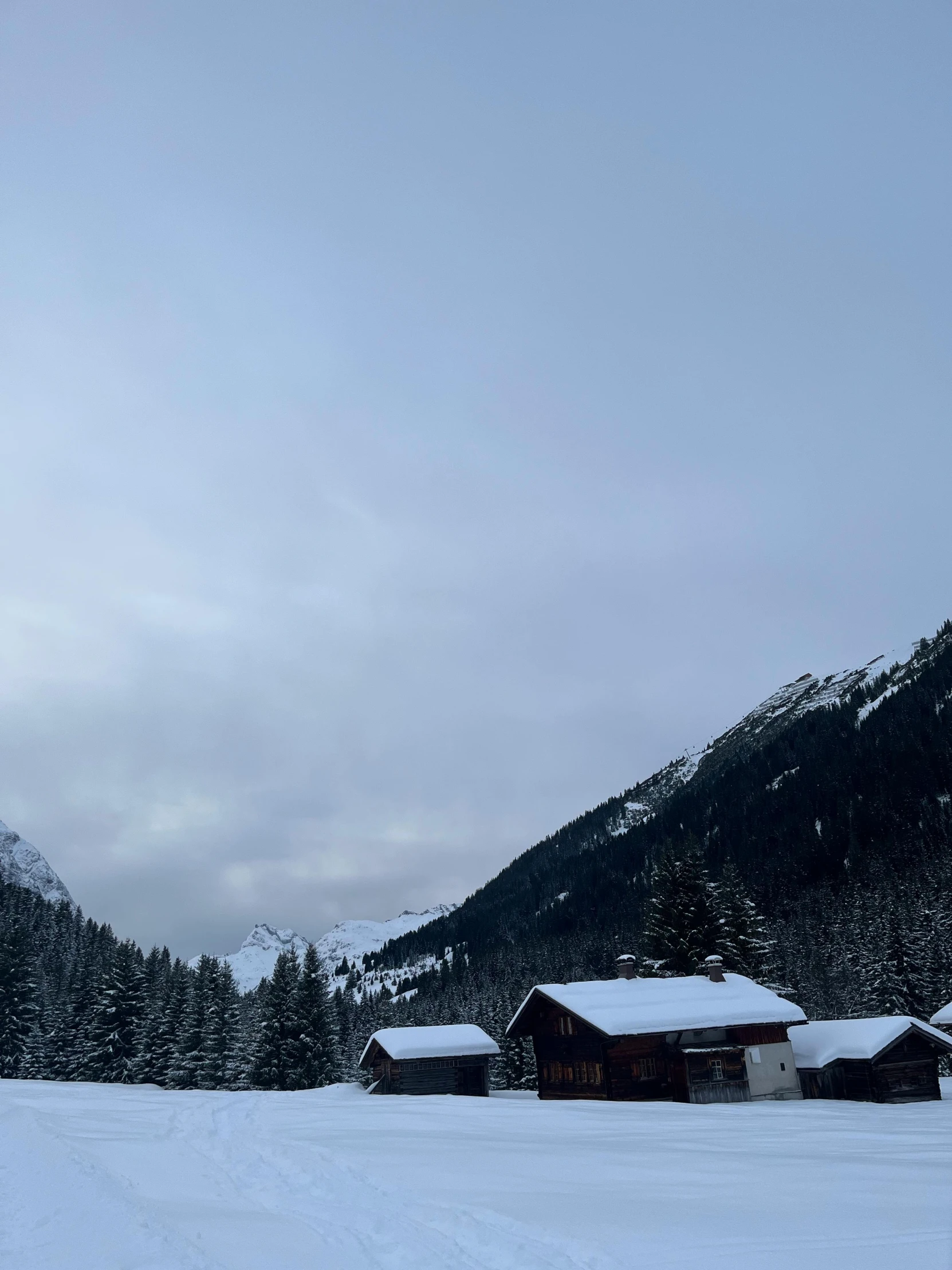 a cabin is seen in front of snowy mountains