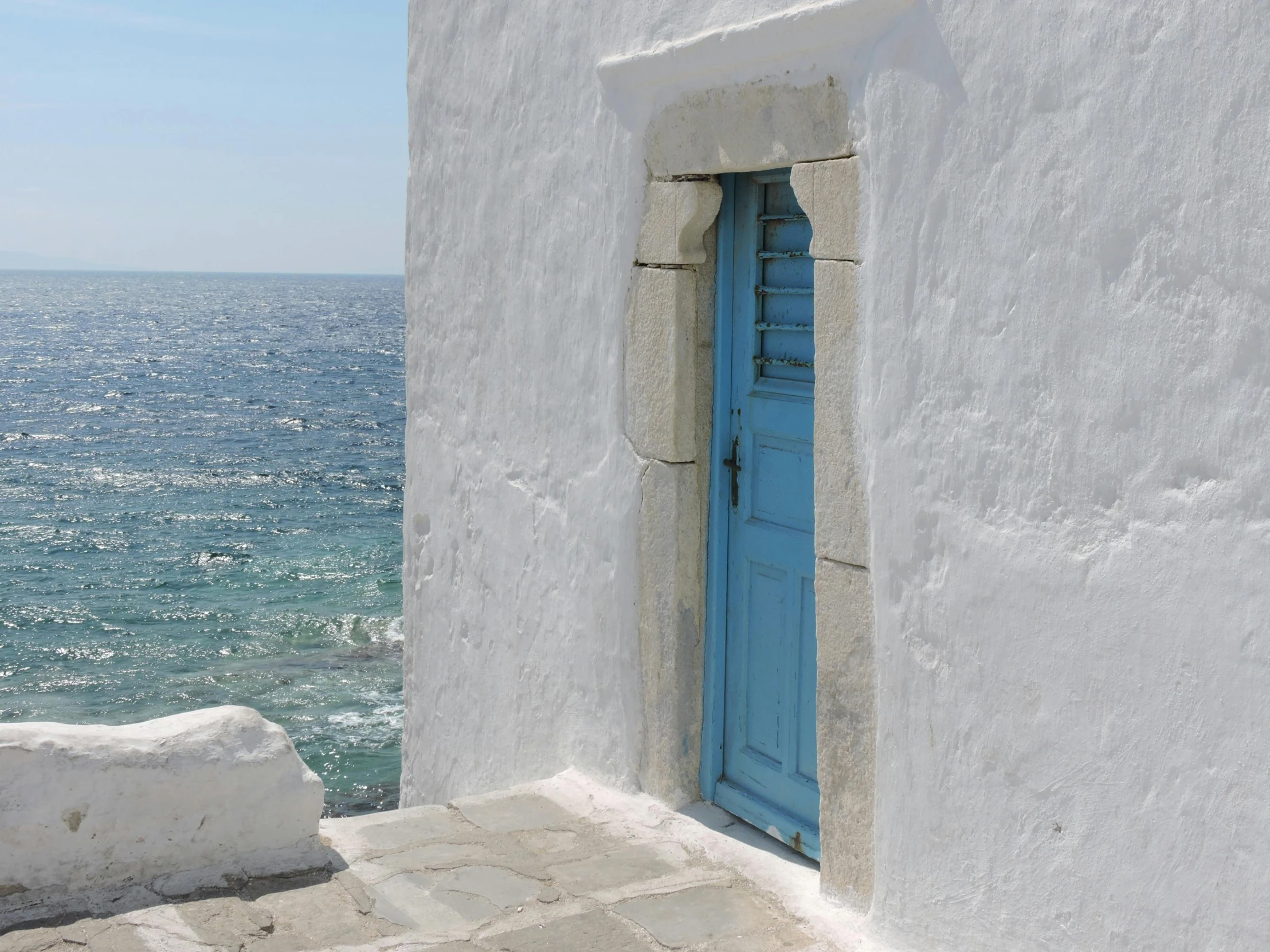 a window and door to an ancient whitewashed building