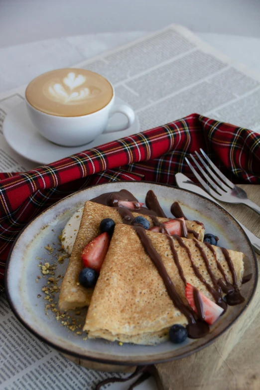 a pancake with strawberries on it next to some syrup and coffee