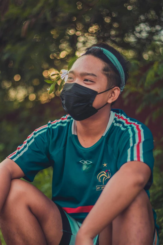 a man in a blue shirt is wearing a black mask and crouching