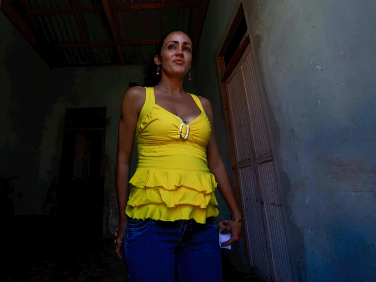 a woman standing outside of a door way wearing yellow