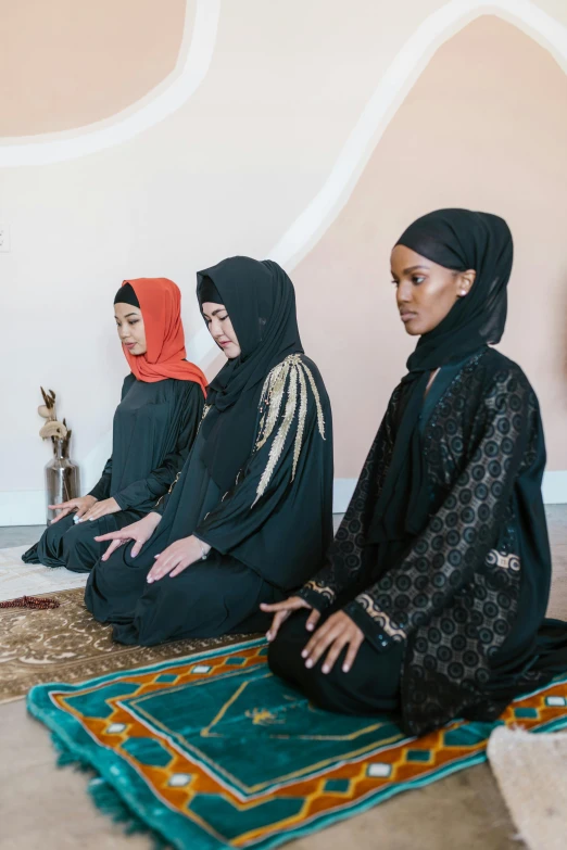 three women are sitting on the floor with their heads turned