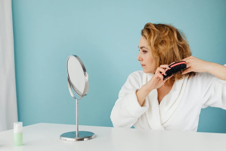 woman in white shirt blow drying her hair