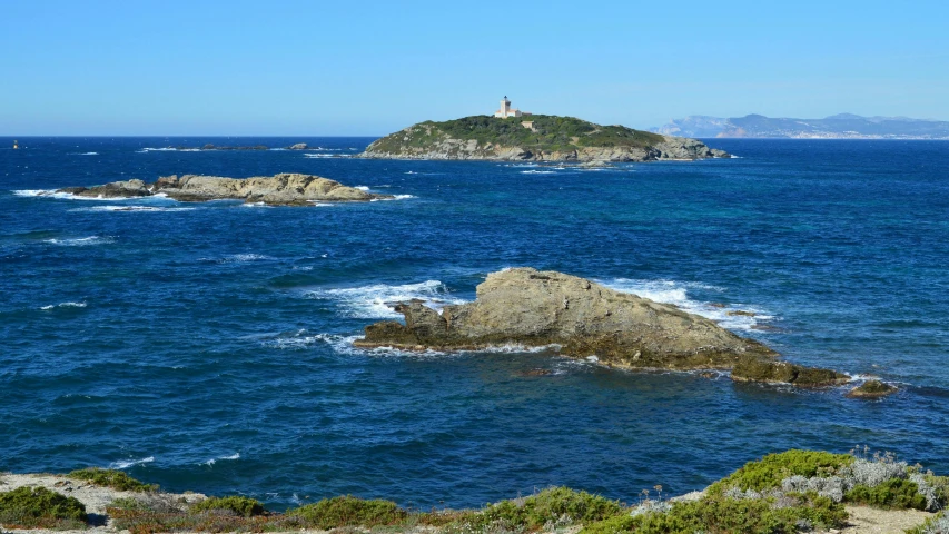 two rocks, one with a light house, and the other with a lighthouse stand on a rocky coast