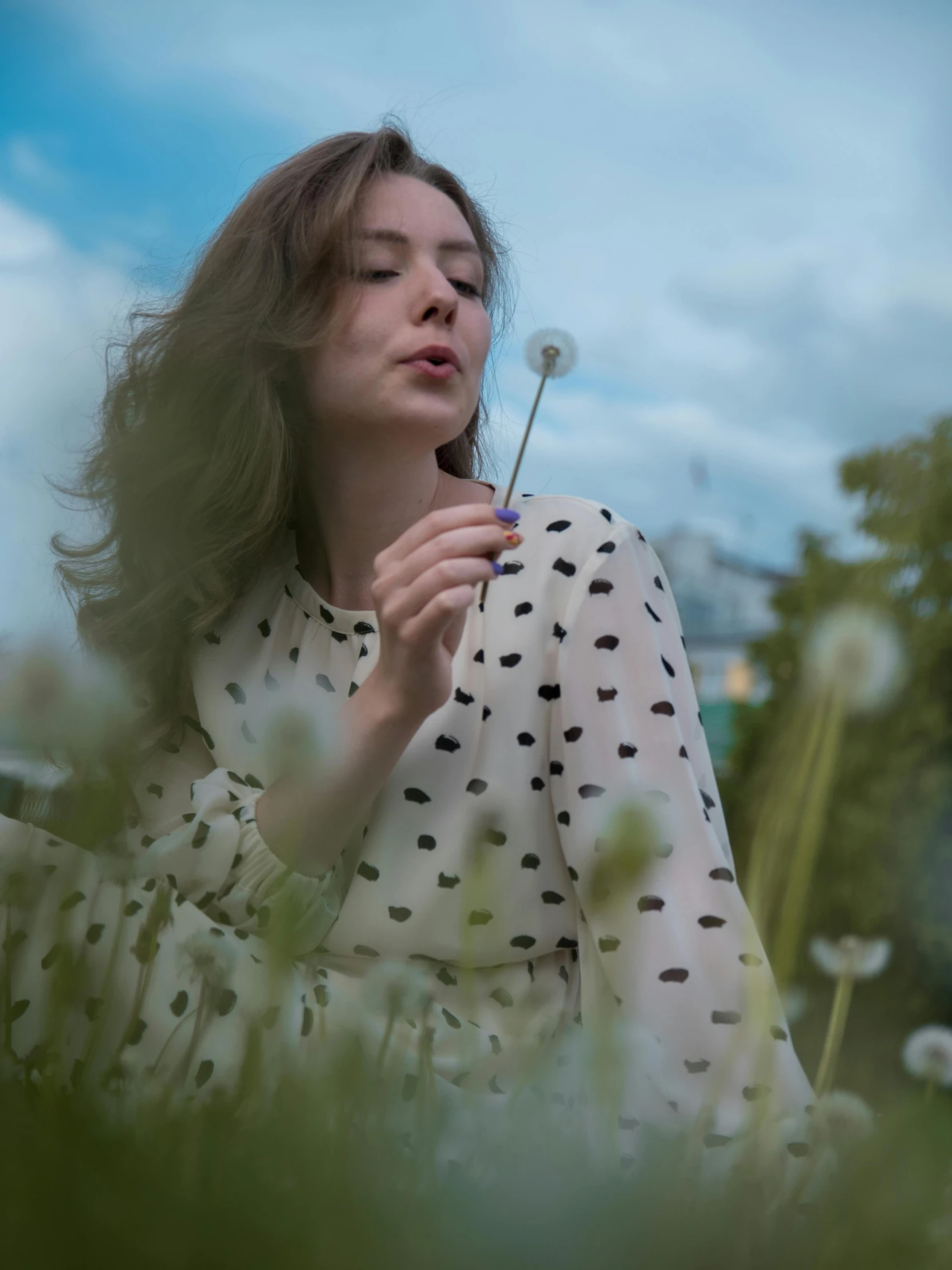 a girl with her eyes closed, blowing the dandelion