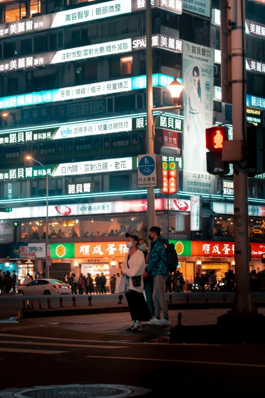 people walking around a street in front of many lit buildings