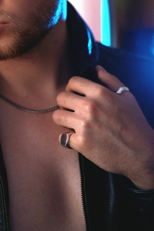 a man that is wearing a ring and necklace