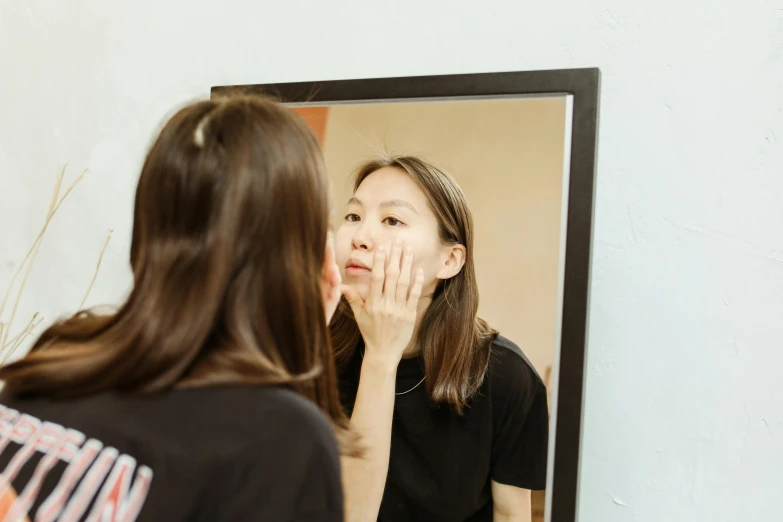 a woman looking in the mirror with a hand on her cheek