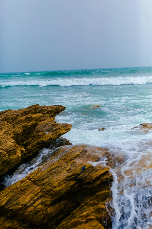 two people swimming in the ocean next to large rocks