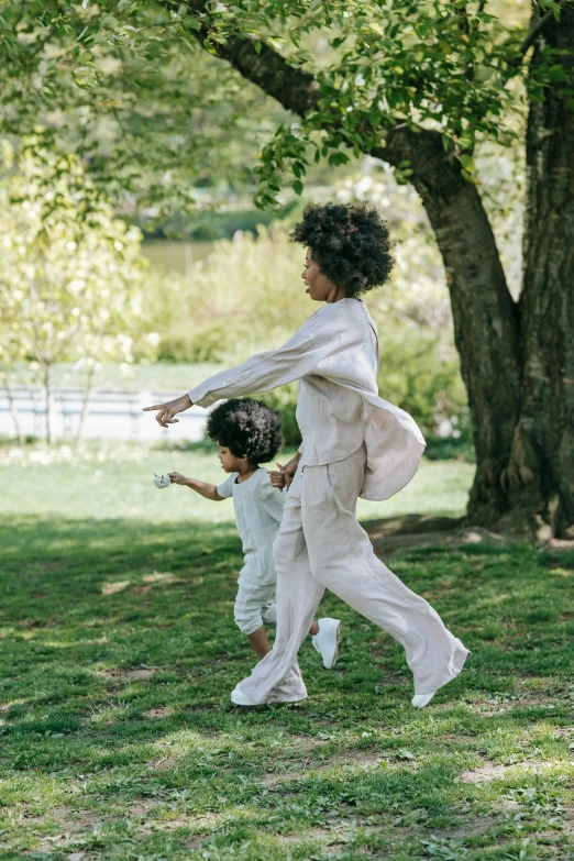 a woman holding onto the back of two young children in white outfits