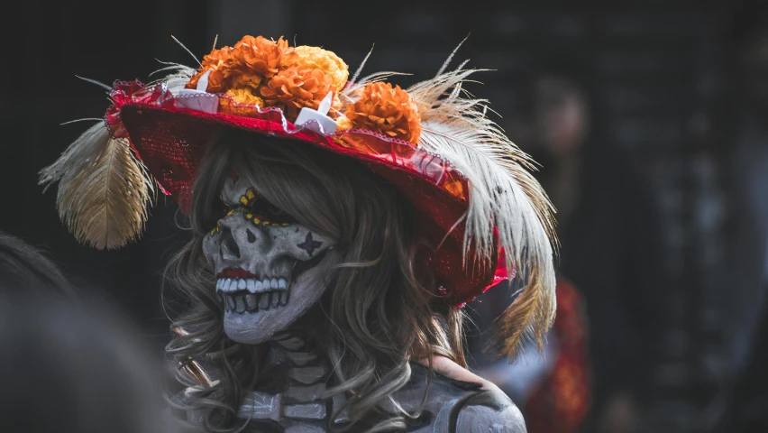 a woman wearing skeleton makeup and a large hat with orange flowers