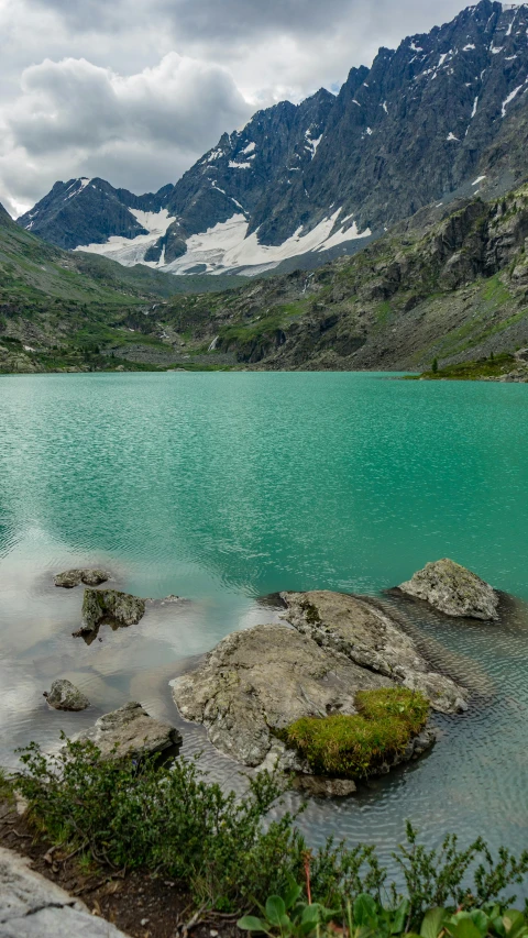 some green water grass rocks and mountains