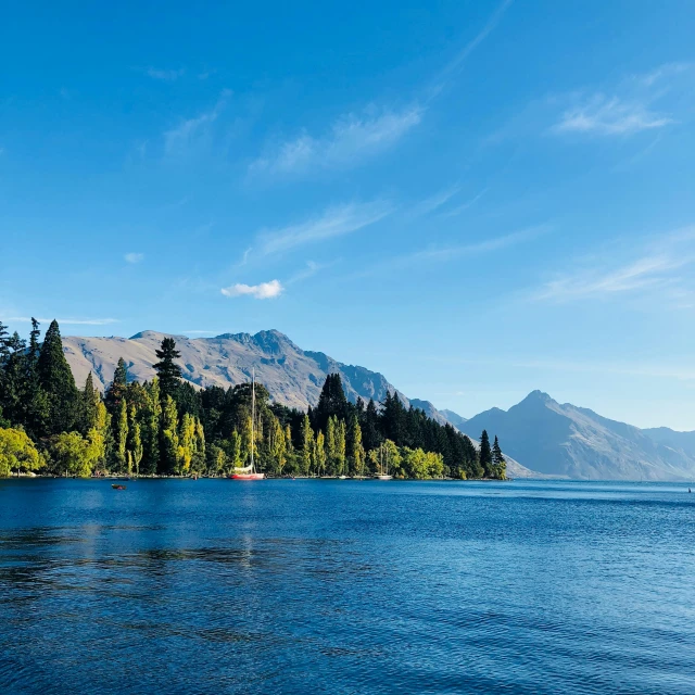 the calm blue water at a lake with trees on it