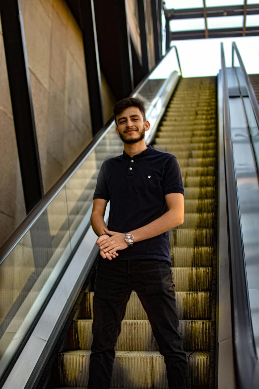 a man is posing at the bottom of an escalator