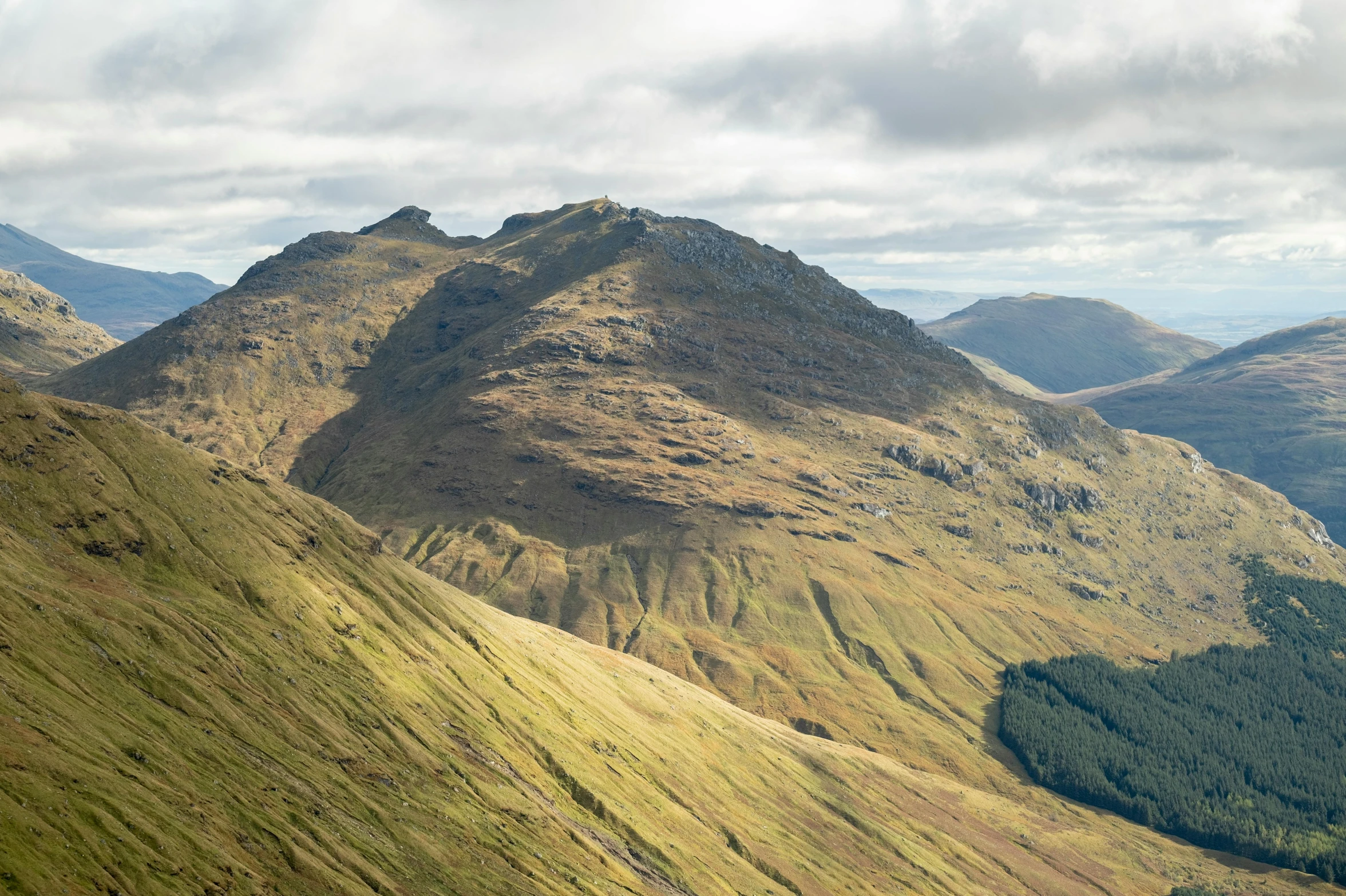 the mountain peaks rise above a lush green valley