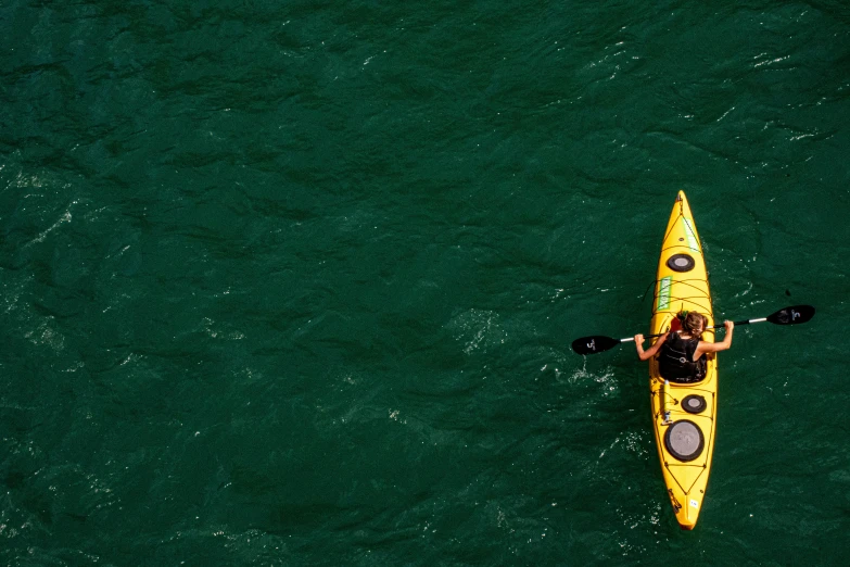 an aerial view of a person in a yellow kayak