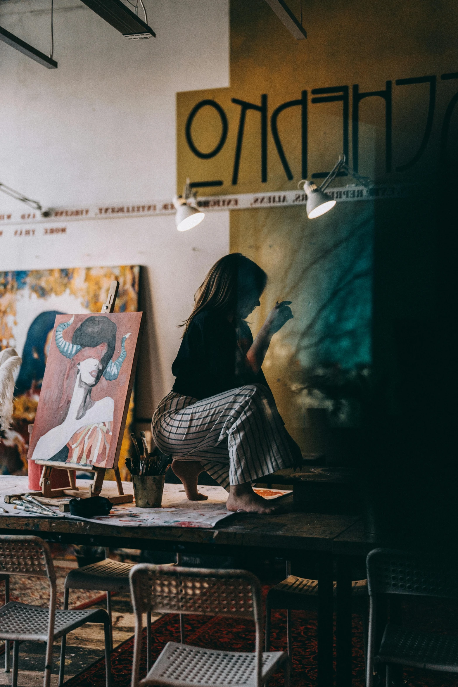 the girl is sitting on her knees by an easel with a dog in her lap