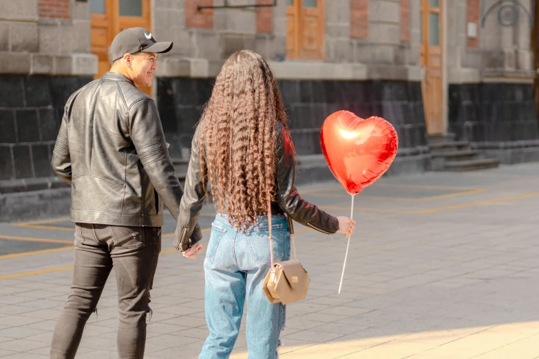 a man and a woman holding a heart shaped balloon