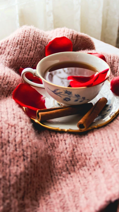 a cup of tea, cinnamon sticks and candy on a cloth