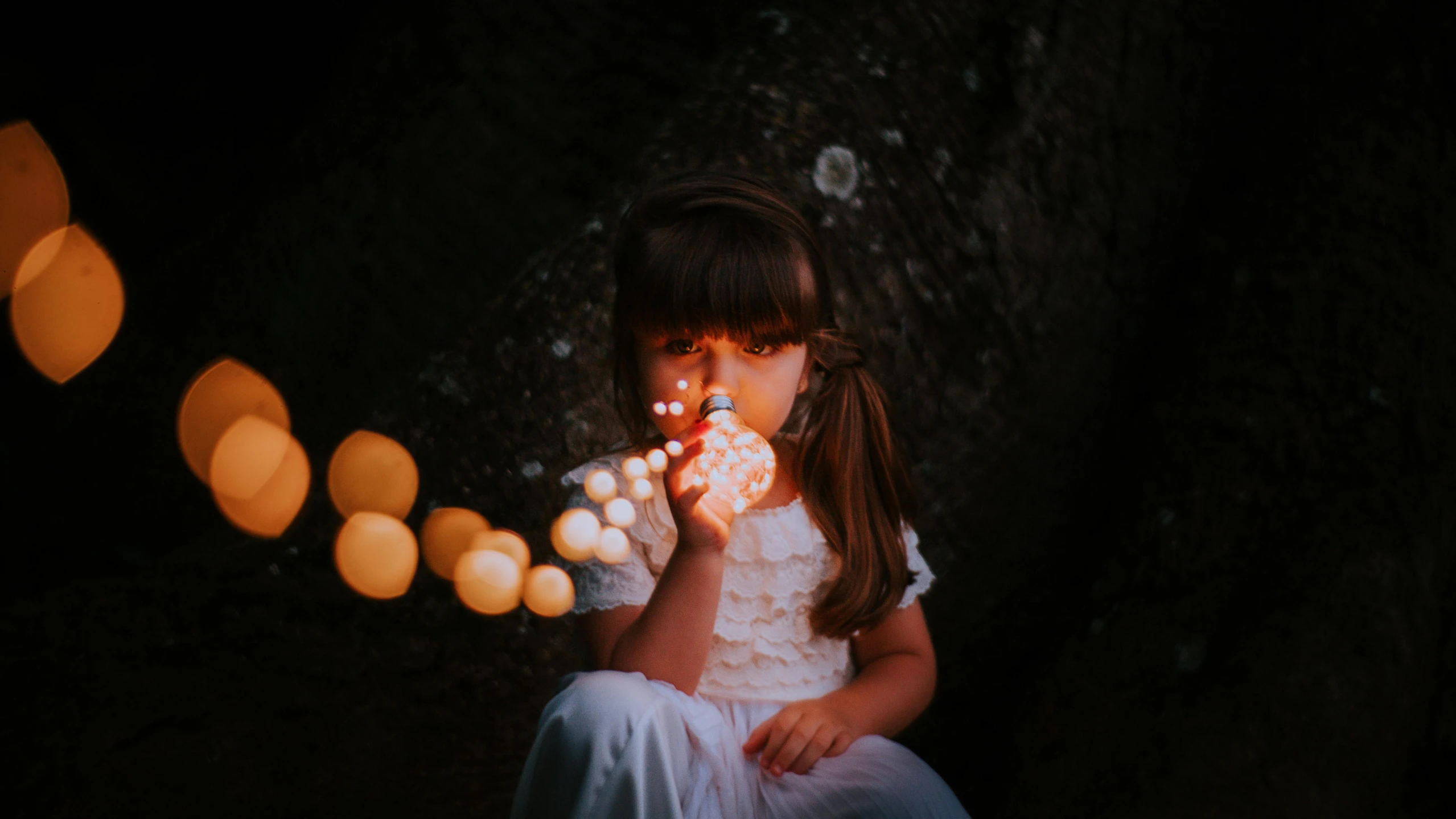 the girl is eating the pastry on the string of lights