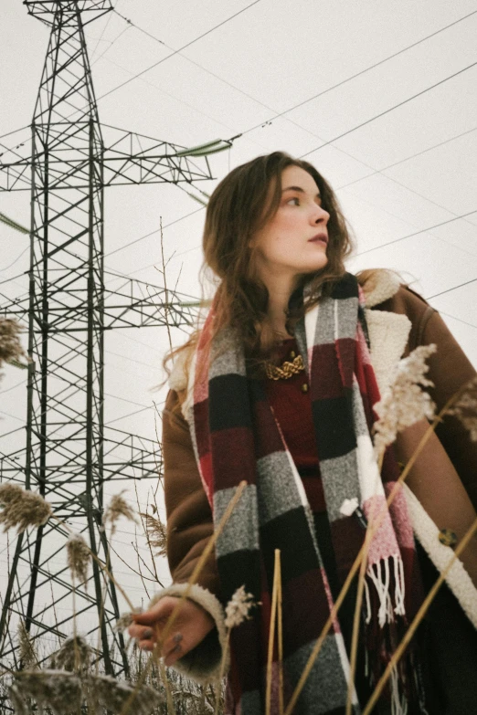 a woman wearing an overcoat is standing in the field