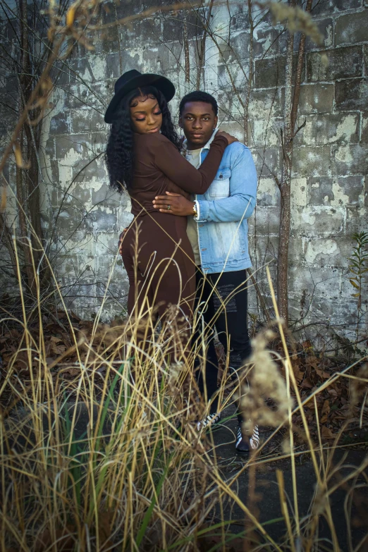 man and woman emcing while standing next to a stone wall