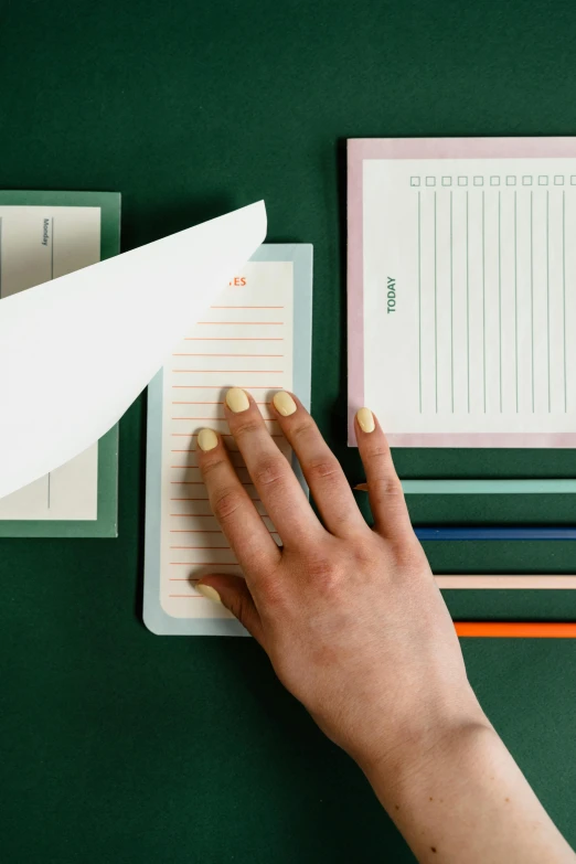 a hand on top of a notepad with papers on it