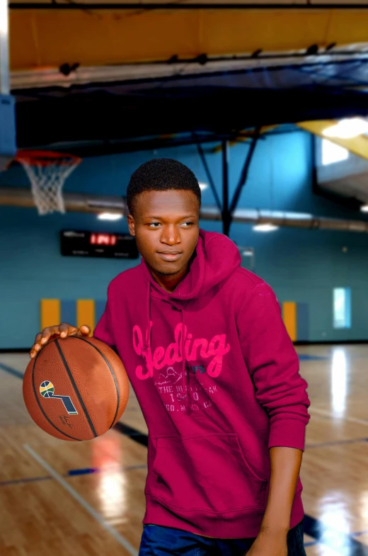 man in red hoodie holding a basketball on a gym floor