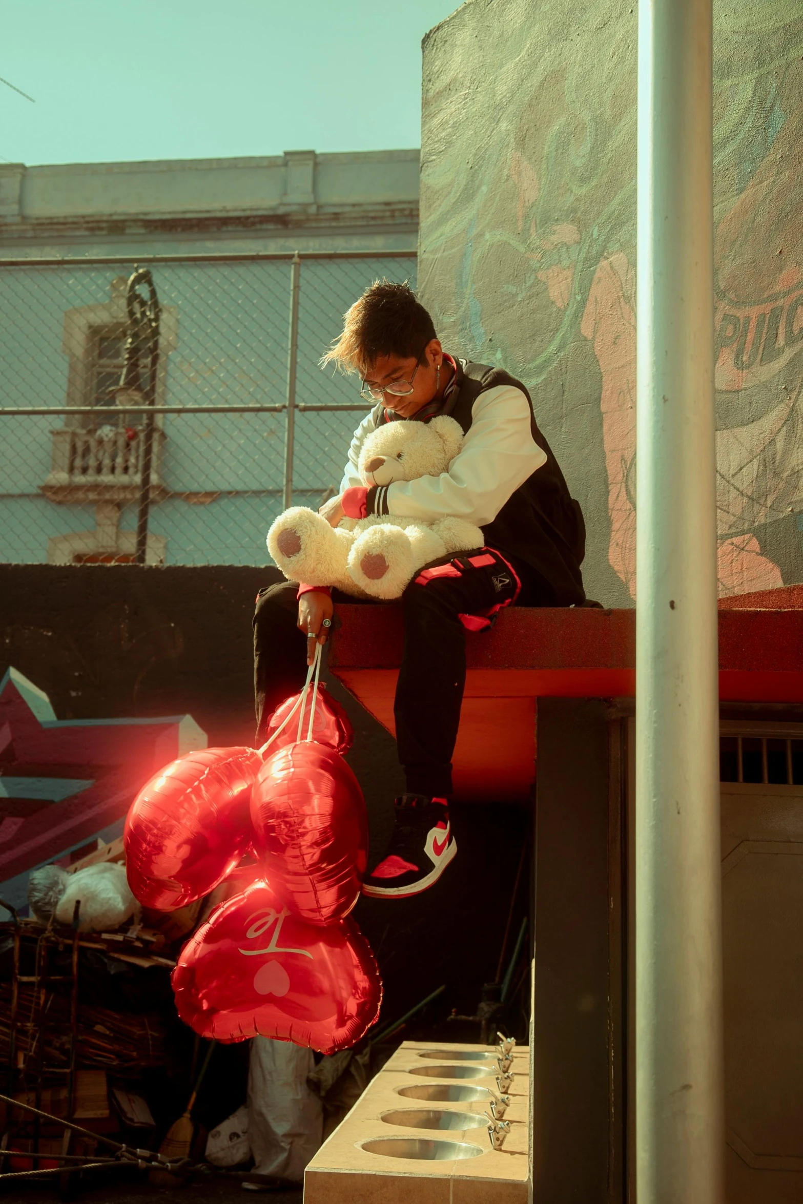 the person sits on the curb with his teddy bear