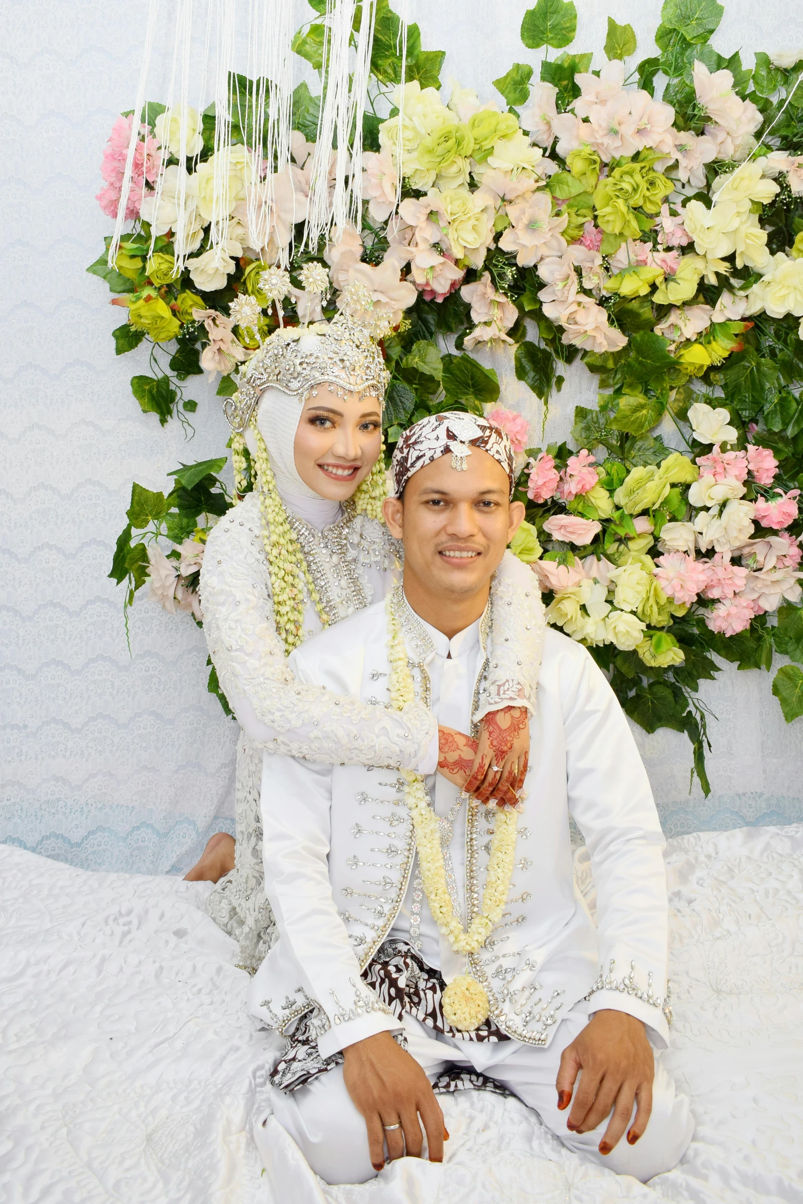 a man and woman in wedding attire sit on a bed