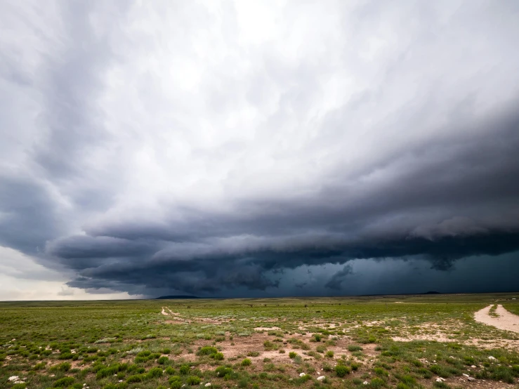 the dark clouds loom over the green plain